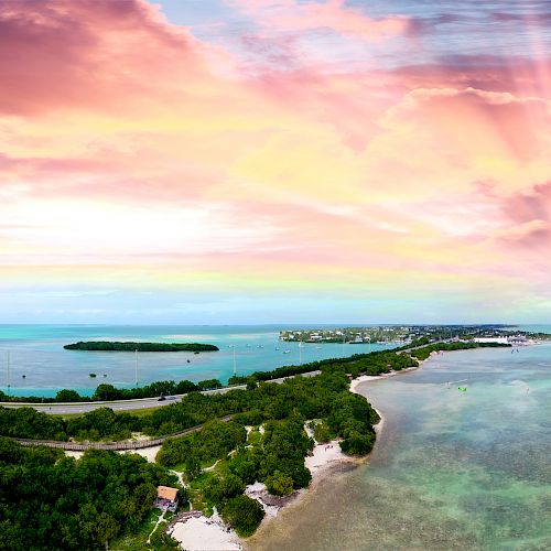 A breathtaking panoramic view of an island surrounded by turquoise waters, with lush greenery and a dramatic, colorful sunset sky overhead.