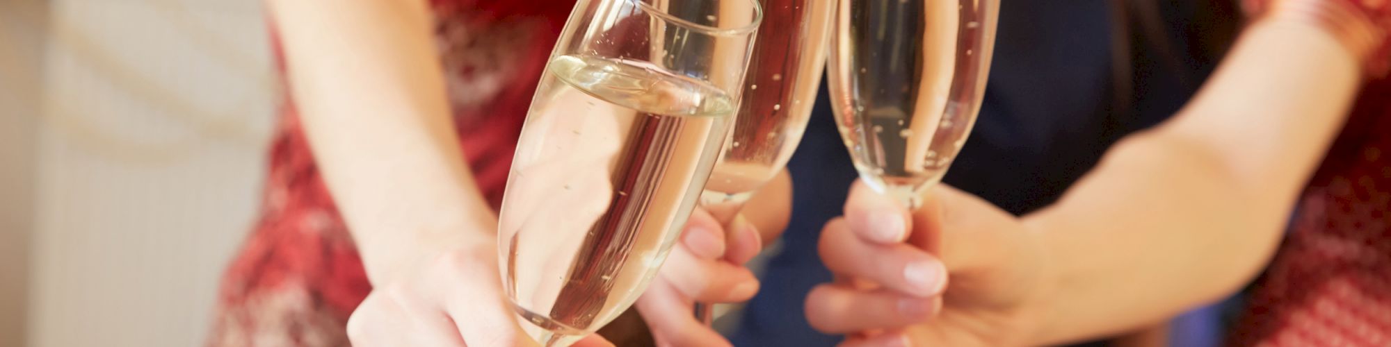 Three people are clinking champagne glasses in a celebratory toast. They appear to be in a festive setting, likely participating in a joyful event.