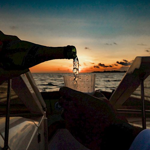 Champagne being poured into a glass on a boat at sunset, creating a relaxing and scenic atmosphere over the water.