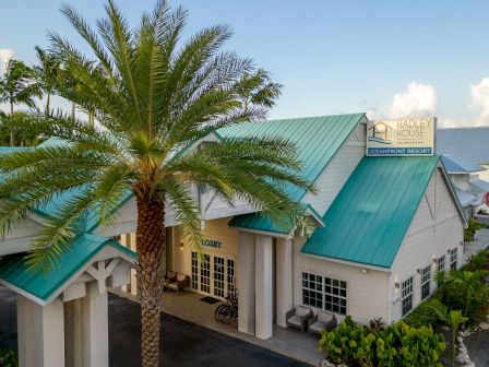 Tropical resort building with green metal roofs, a palm tree, and signs reading Hadley House and Oceanfront Resort.