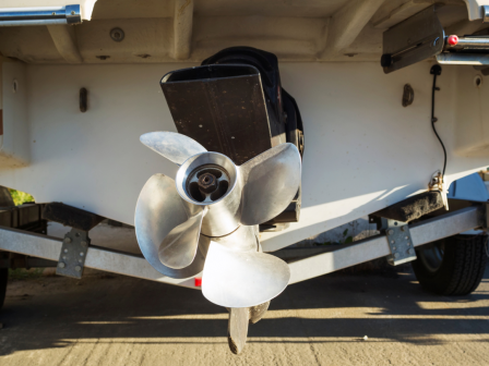 This image shows the rear end of a boat on a trailer, focusing on the boat's propeller and outboard motor.