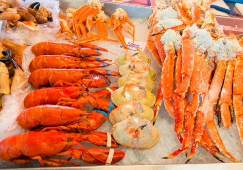 Fresh shrimp and other seafood on ice&mdash;orange lobster-like tails and red-spotted king prawns laid out on trays.