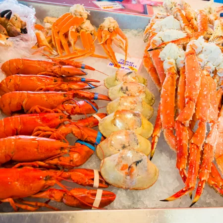 Fresh shrimp and other seafood on ice&mdash;orange lobster-like tails and red-spotted king prawns laid out on trays.